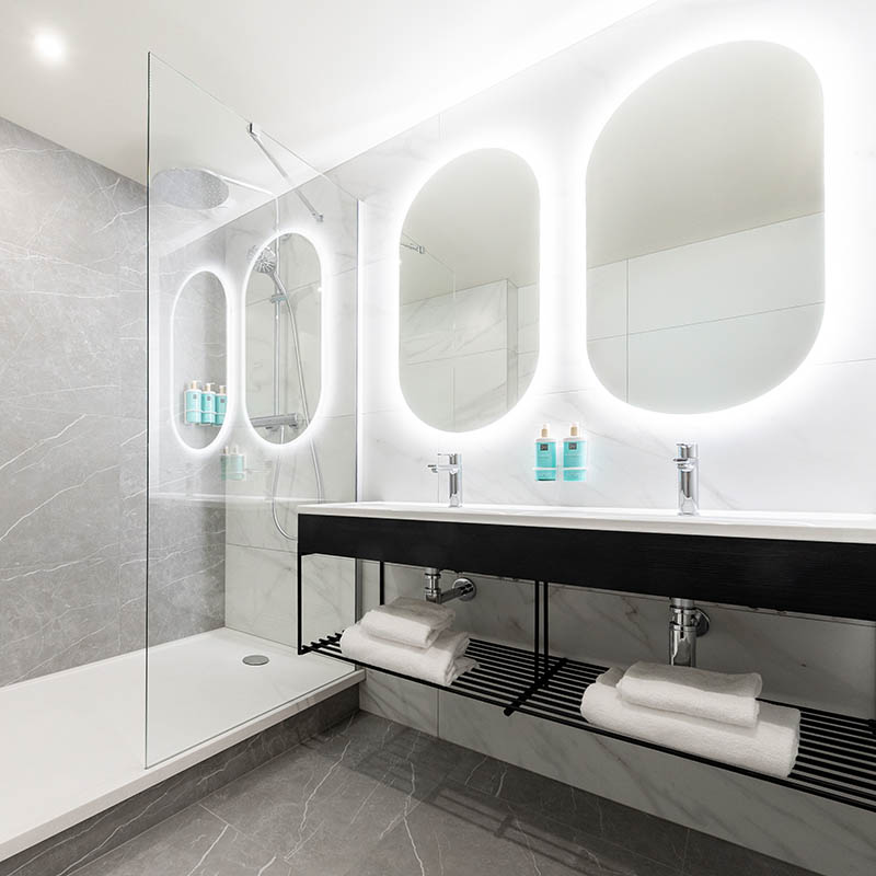 Photographe hôtel Marseille : salle de bain de luxe design, marbre gris et miroirs rétroéclairés, shooting pro en PACA.