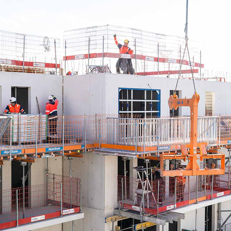 Photographe BTP Marseille : ouvriers sur un chantier d'immeuble en béton avec grue et équipements de sécurité AlphiSafe.