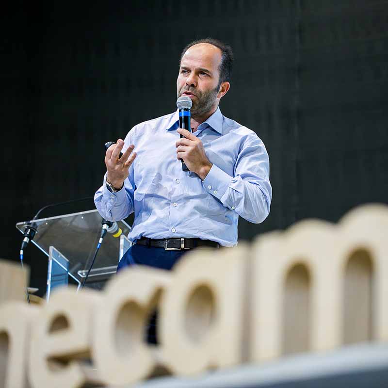Photo événement entreprise Marseille : un orateur en chemise bleue s'exprime au micro lors d'un congrès professionnel.
