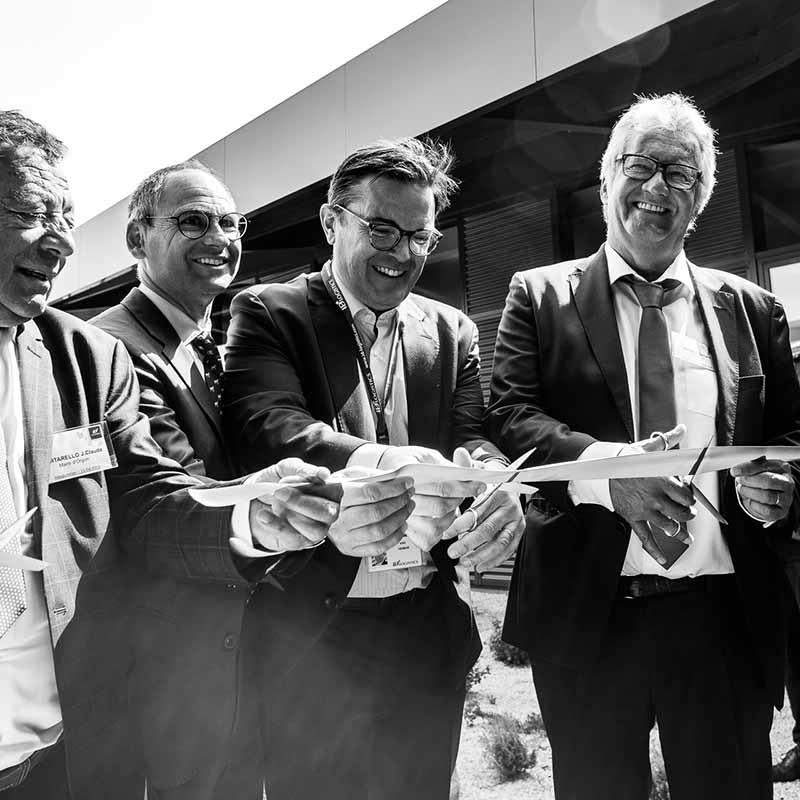Photo reportage Marseille : quatre hommes en costume souriants lors de la découpe d'un ruban inaugural pour une entreprise.