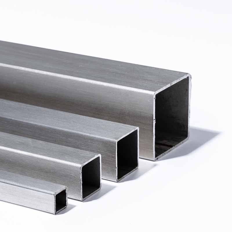 Photographie packshot de quatre profilés métalliques carrés en acier brossé alignés sur un fond blanc épuré.