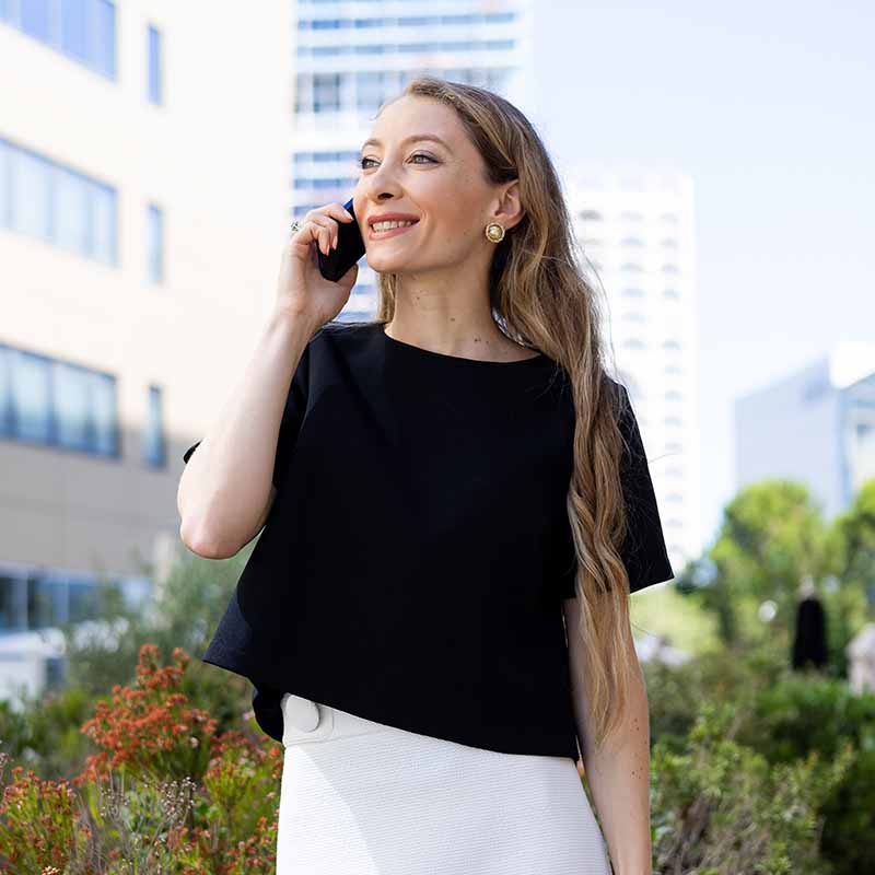 Portrait corporate d'une femme d'affaires en tenue blanche devant un immeuble de bureaux à Marseille.