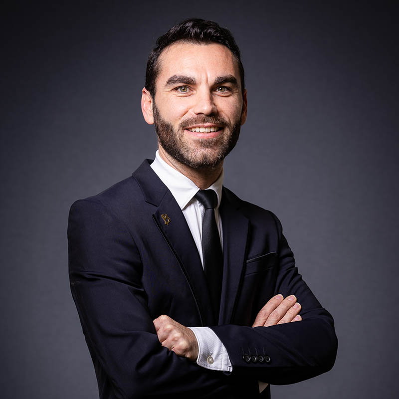 Portrait corporate d'un homme souriant en costume cravate sur fond gris dans un studio à Marseille.