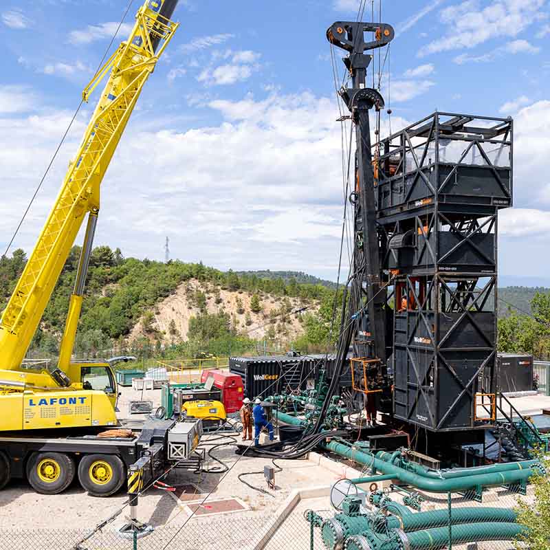 Photo industrielle Marseille : tour de forage noire et grue Lafont jaune sur un site de gaz en extérieur sous un ciel bleu.
