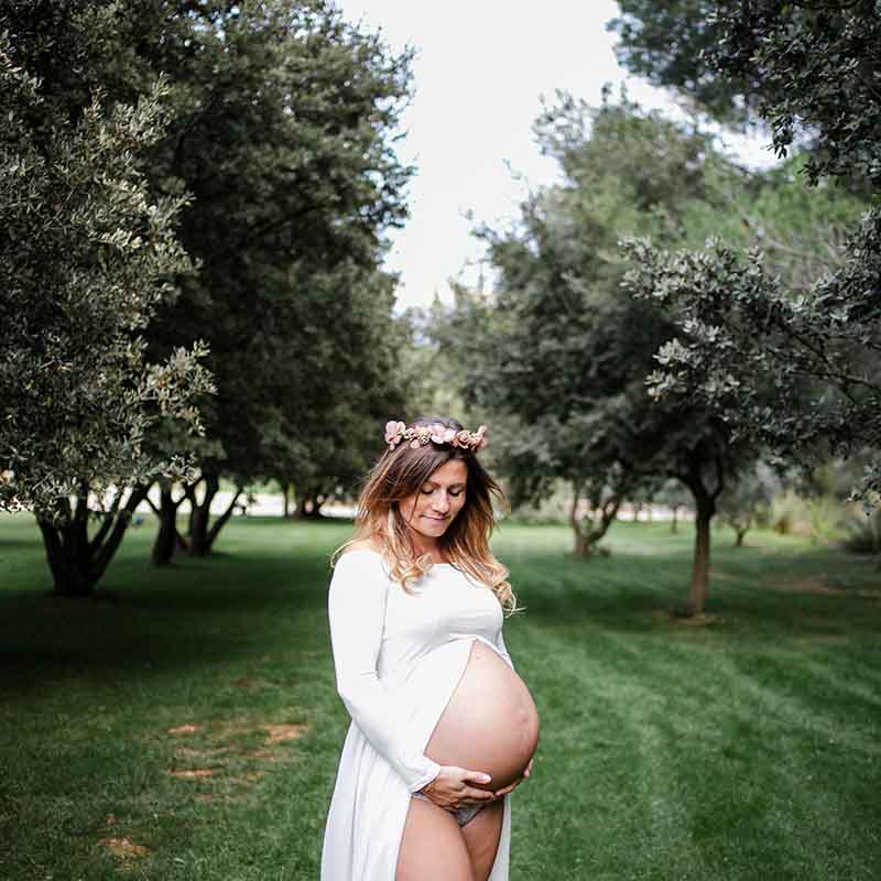 Photographe grossesse Marseille : femme enceinte avec couronne de fleurs dans un champ d'oliviers en Provence.