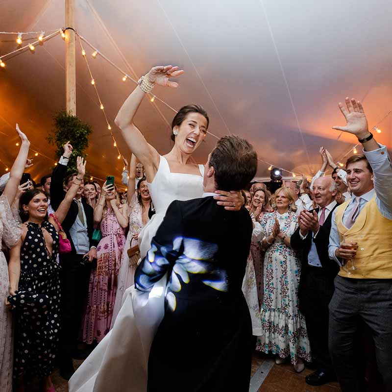 Jeune mariée portée par son époux lors d'une danse endiablée pendant la soirée de mariage en Provence.