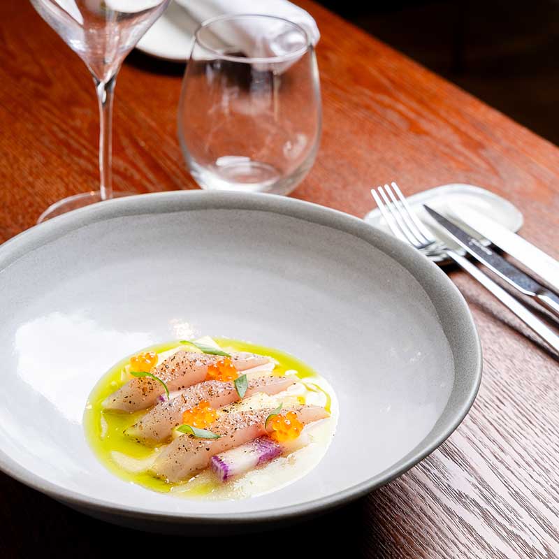 Photographie culinaire d'une assiette gastronomique de poisson cru et œufs de truite dans un restaurant marseillais.