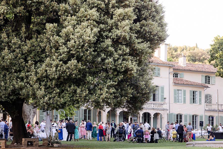 Réception de mariage en extérieur dans le parc de la Bastide de Toursainte à Marseille avec de nombreux invités devant la façade de la bastide.